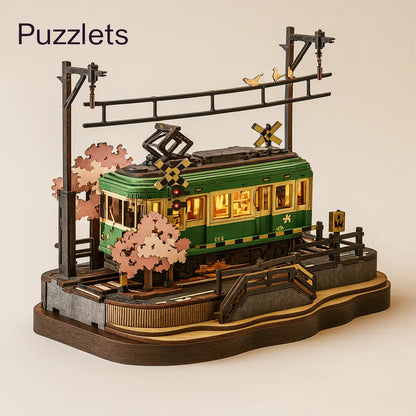 Model of a green tram with cherry blossom trees and a crosswalk sign on a beige background, branded 'Puzzlets'.