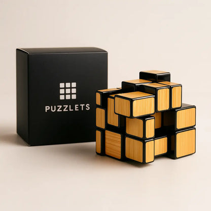Black and gold puzzle cube with 'PUZZLETS' branding on a beige background